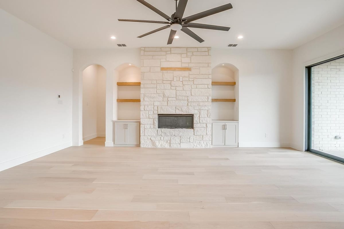 Great room with a stone fireplace, built-in shelving, and a beamed ceiling