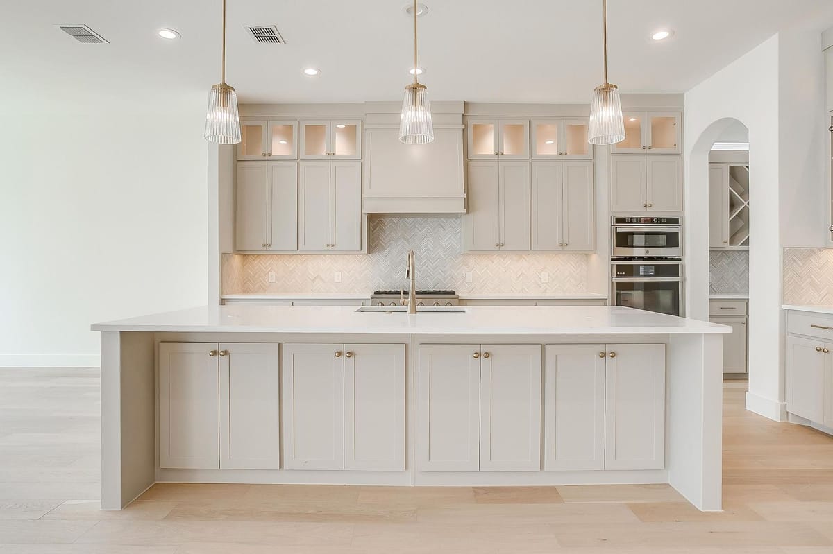 Kitchen with a quartz island, stacked cabinetry, and built-in ovens