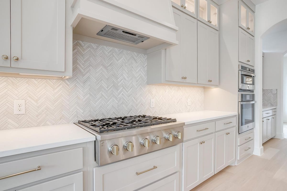 Herringbone tile backsplash behind a professional gas range