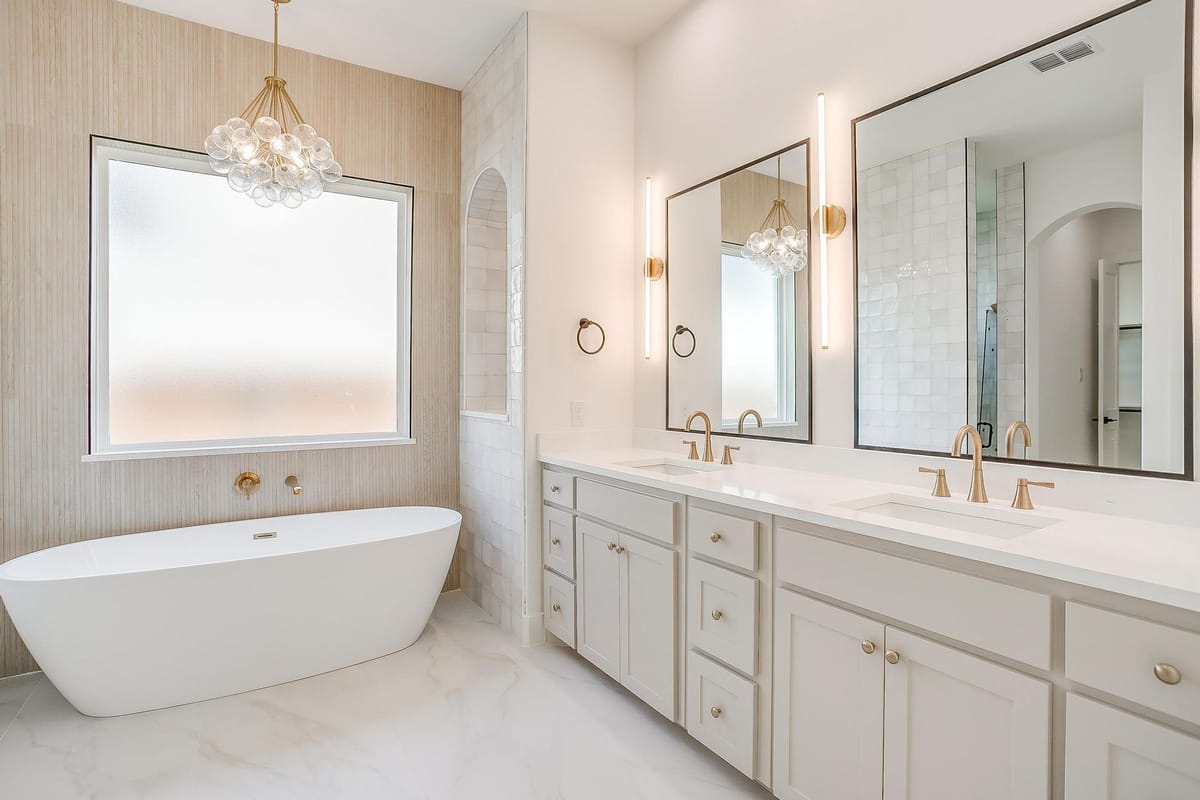 Primary bathroom with a freestanding tub, chandelier, and double vanity