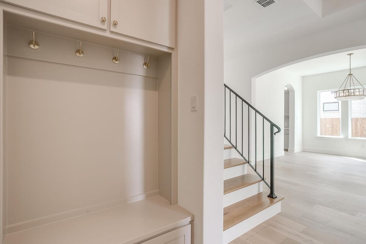 Mud room with a built-in bench, coat hooks, and a view through to the dining room