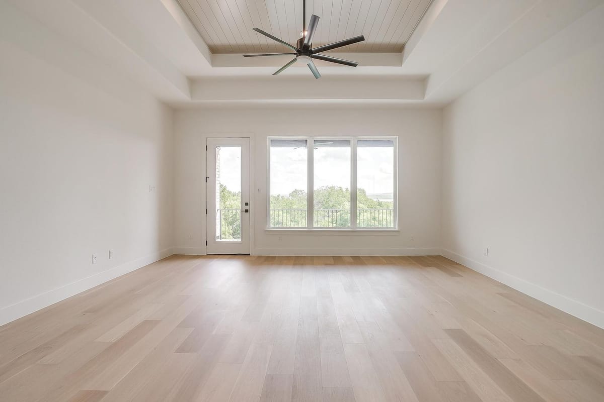 Primary bedroom with a tray ceiling and a wall of windows
