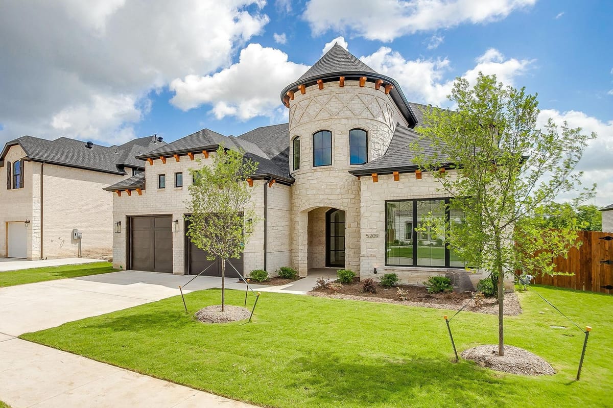 Stone and stucco custom home exterior with a rounded turret entry