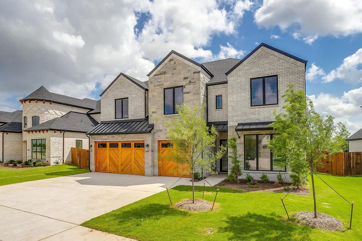 Front elevation of a Parkwood custom home with an arched stone entry and cedar garage doors