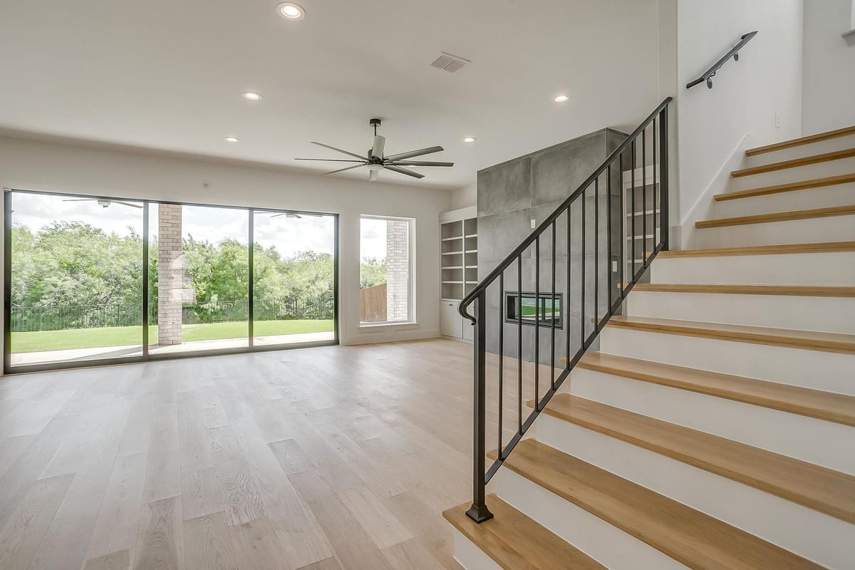 Living room in a Parkwood custom home with floor to ceiling windows and an open stair