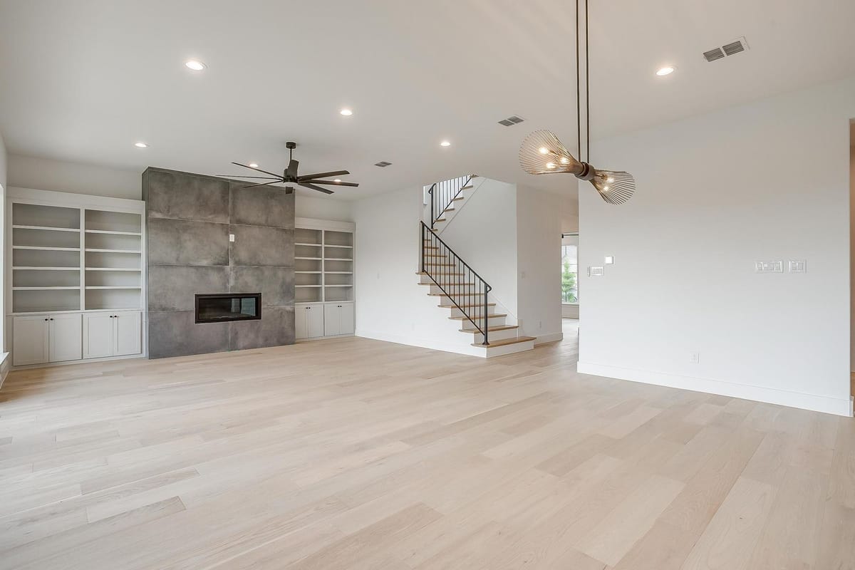 Living area with a tile fireplace surround, built-in shelving, and an open stair