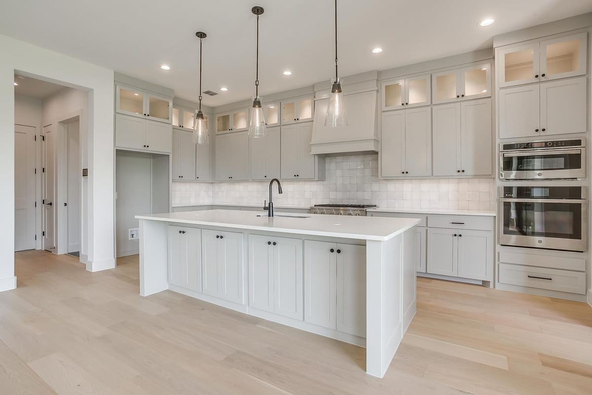 Kitchen island with pendant lighting and a professional range beneath a plaster hood