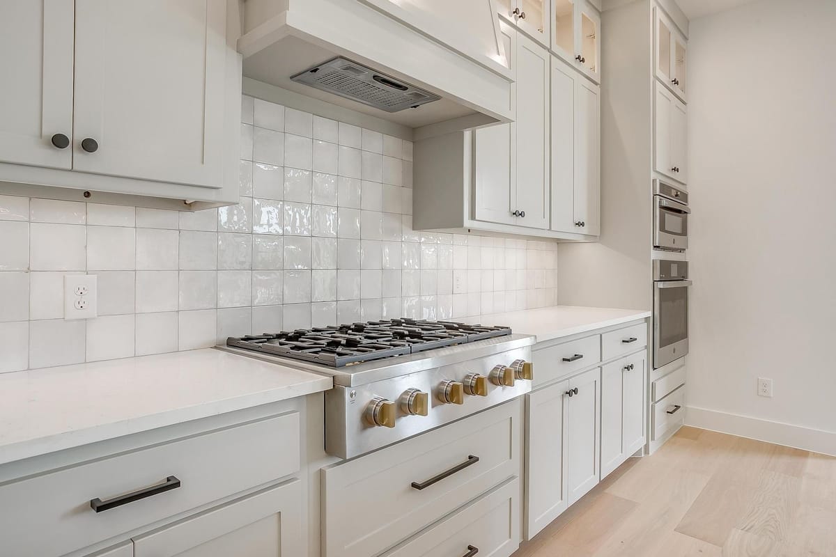Range wall with a tile backsplash, professional gas range, and vent hood