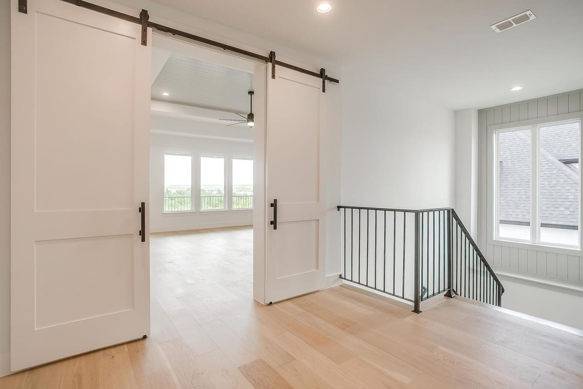 Upstairs landing with a sliding barn door and iron stair railing