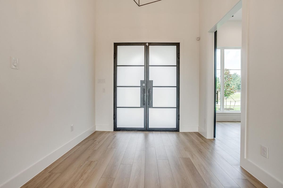Steel and glass double doors opening into a bright room