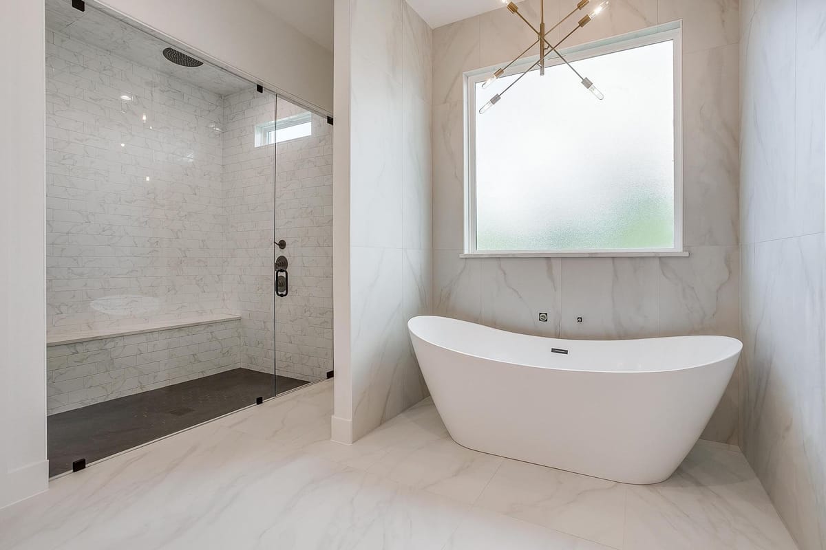 Primary bathroom with a freestanding tub, walk-in shower, and marble tile