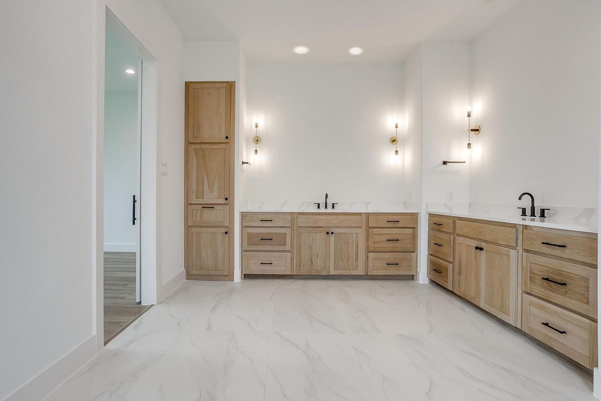 Double vanity with natural wood cabinetry and wall sconces